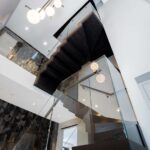 Zigzag oak staircase with frameless glass balustrades and globe pendant lights, London house